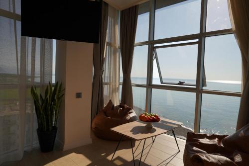 ein Wohnzimmer mit einem Tisch und einem großen Fenster in der Unterkunft RUMI Hotel in Batumi