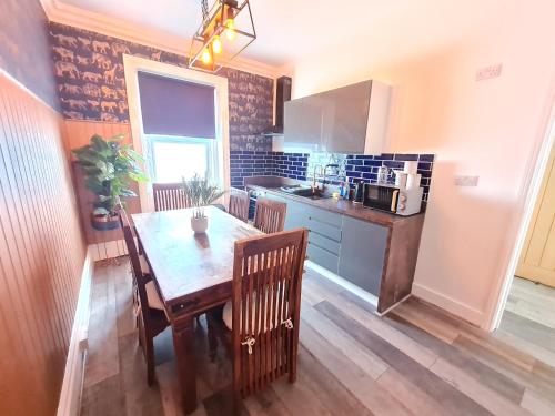 eine Küche mit einem Holztisch mit Stühlen, einem Tisch und einem Tisch in der Unterkunft Yellow Lemur Apartment - Lemur Lodge - Short Stroll to the Beach - Free Wifi in Bournemouth