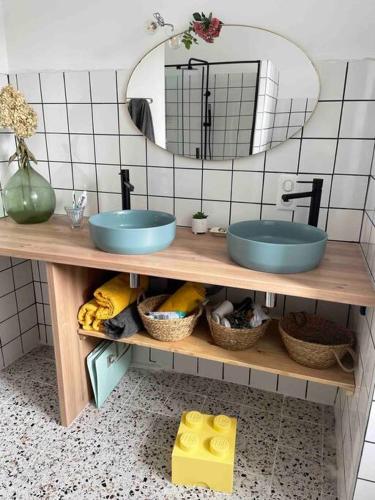 La salle de bains est pourvue de 2 lavabos bleus et d'un miroir. dans l'établissement Maison familiale 8 p en vallée de Dordogne - Lot, à Tauriac