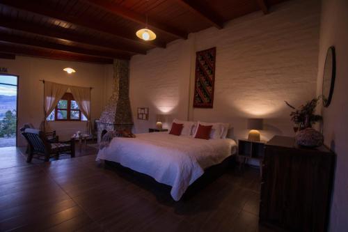 a bedroom with a large bed and a large window at Tuki Llajta - Pueblo bonito Lodge in Huancayo