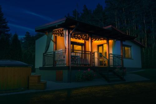a house with a porch lit up at night at Sławica Inn domek letniskowy nad jeziorem in Sławica