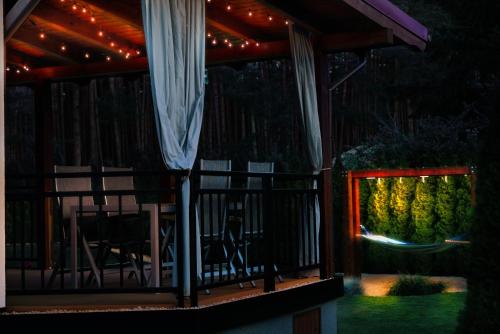 a screened in porch at night with a table and chairs at Sławica Inn domek letniskowy nad jeziorem in Sławica