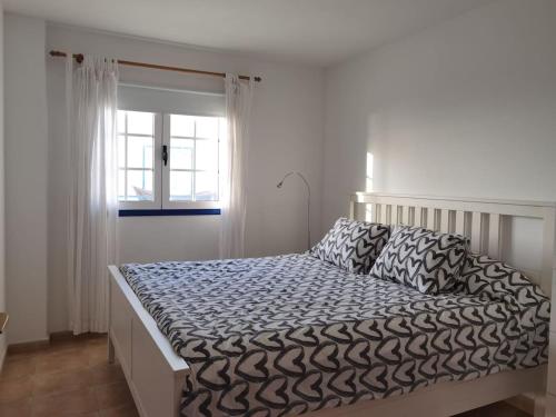 a bed in a white room with a window at Brisa del mar in La Santa