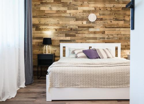 a bedroom with a white bed and a wooden wall at Sławica Inn domek letniskowy nad jeziorem in Sławica