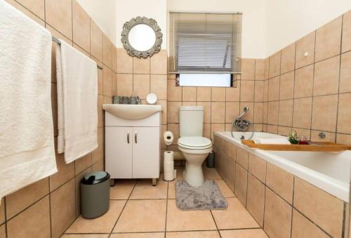a bathroom with a toilet and a tub and a sink at Havens corner in Sandton
