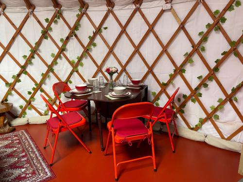 uma sala de jantar com cadeiras vermelhas e uma mesa numa tenda em The Yurts at Burnt House Farm em Newport