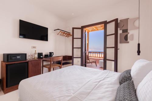 a bedroom with a bed and a desk with a television at Akre Hotel - Designed for Adults in Naxos Chora