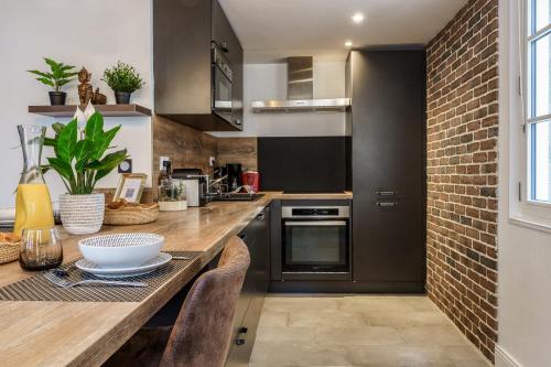 cocina con encimera y pared de ladrillo en Le Baleschoux - PrestiPlace Tours, en Tours