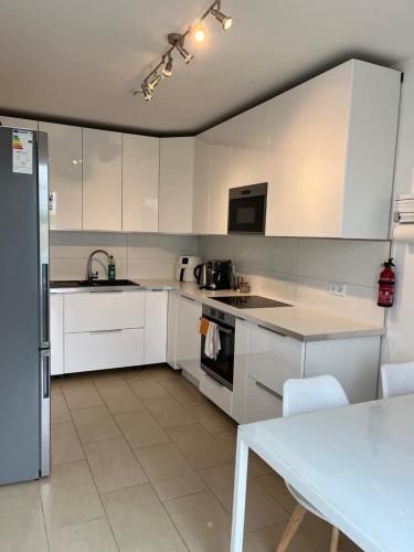una cucina con armadi bianchi, tavolo e frigorifero di Private Room near Hannover Fair ad Hannover