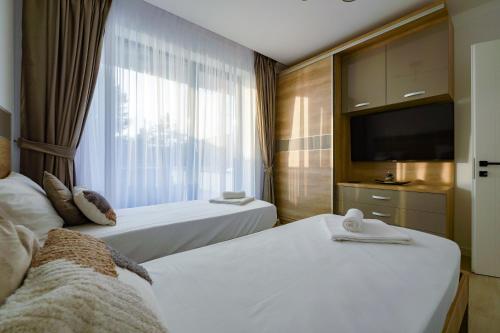 a hotel room with two beds and a television at Blue Luxury Apartment Lake On in Mamaia