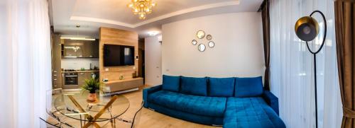 a living room with a blue couch and a glass table at Blue Luxury Apartment Lake On in Mamaia