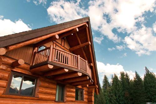 a log cabin with a balcony on the side of it at Revelstoke House Luxury Log House at Base of Resort in Revelstoke