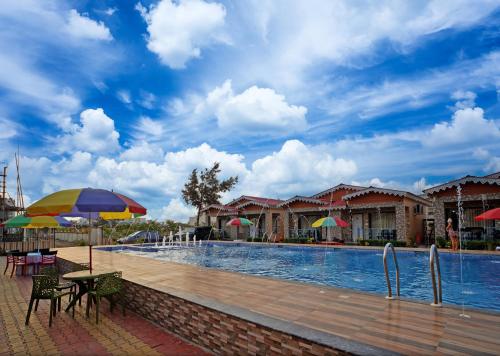 a swimming pool with tables and chairs and umbrellas at AQUA BLUE RESORT PRIVATE LIMITED in Mandarmoni