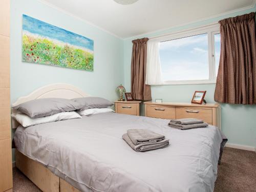 a bedroom with a bed with two towels on it at Hookhills Holiday Home in Goodrington