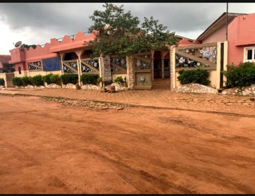 ein rosafarbenes Gebäude mit einer Schotterstraße davor in der Unterkunft Hôtel cœur des montagnes in Abomey