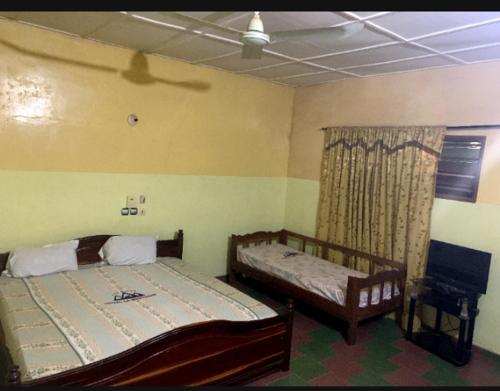 1 dormitorio con 2 camas y ventana en Hôtel cœur des montagnes en Abomey