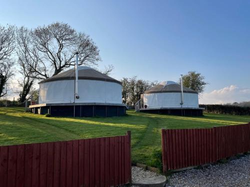 two domed buildings in a field with a fence at The Yurts at Burnt House Farm in Newport