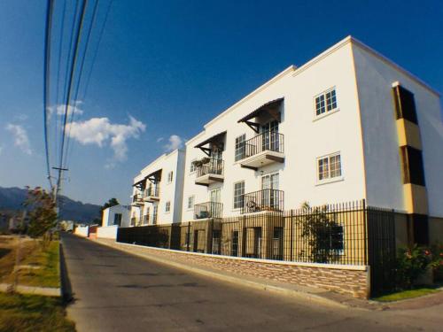 a large white building on the side of a street at Paseo de la Arboleda apartamento in Quetzaltenango