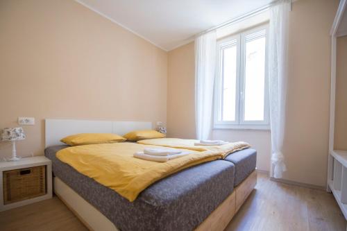 a bedroom with a bed with yellow sheets and a window at Apartments E & E Piran in Piran