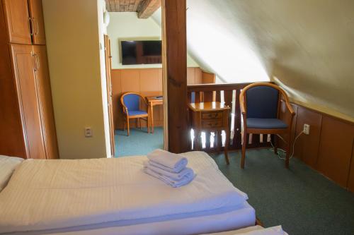 a bedroom with a bed and two chairs and a table at Penzion Zvonice Hojná Voda in Horní Stropnice