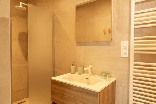 a bathroom with a white sink and a shower at De Gulle Beemden in Hulshout