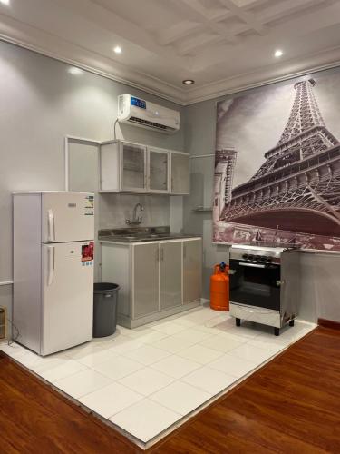 a kitchen with a refrigerator and a painting of the eiffel tower at غرفة وصالة في أبها in Abha