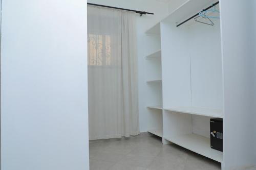 a room with white walls and a white cabinet at SILVER OAKS HOTEL Boma in Fort Portal
