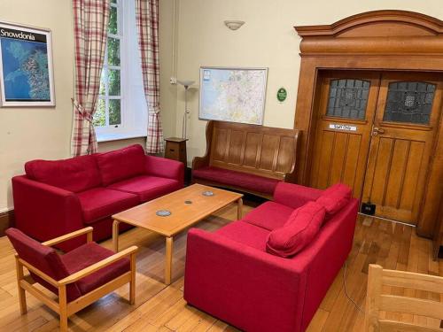 a living room with two red couches and a table at Marle Hall - Dorm Rooms (Yellow) in Llandudno Junction