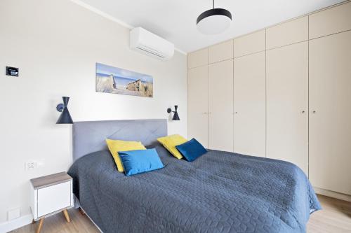 a bedroom with a bed with blue and yellow pillows at Solaris Darłówko Premium Emilia Strupiechowska in Darłowo
