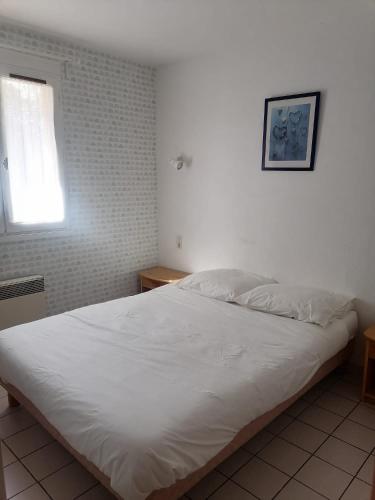 a white bed in a bedroom with a window at The Gare Gondrin in Gondrin