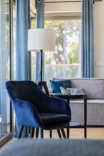 a living room with a blue chair and a couch at Solaris Darłówko Premium Emilia Strupiechowska in Darłowo