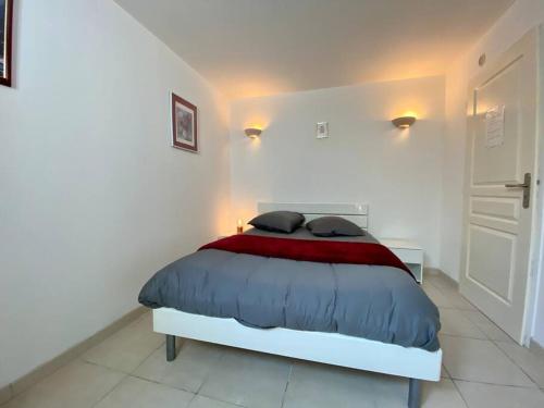 a white bedroom with a bed with a red blanket at Gite Thym spa au coeur d'une oliveraie des Corbières in Saint-Jean-de-Barrou