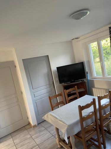 une salle à manger avec une table et des chaises et une télévision dans l'établissement Petite maison avec 2 chambres, à Bussy