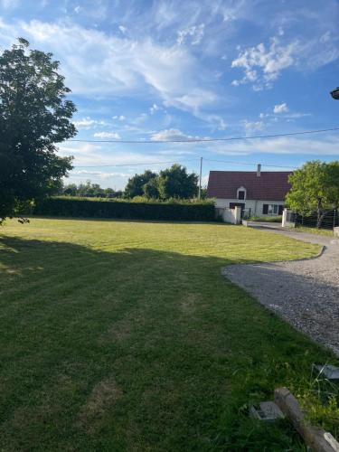 un gran campo de césped con una casa en el fondo en Petite maison avec 2 chambres, 