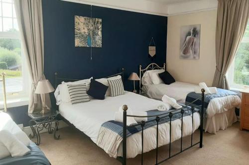 two beds in a bedroom with blue walls at Beaford Country House in Winkleigh