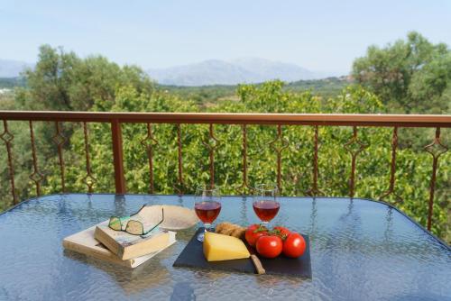 a glass table with two glasses of wine and cheese at Eucalyptus Villa in Gonia