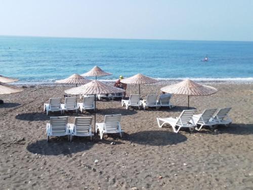 a group of chairs and umbrellas on a beach at Mersin condominium Life City with pool and sea in Erdemli