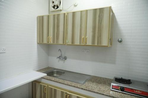 a kitchen with wooden cabinets and a sink at RED-7 - Alwadi Salalah in Salalah