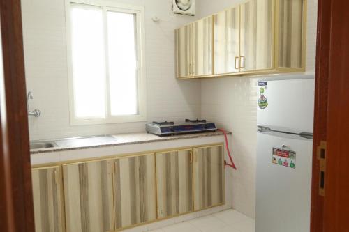 a kitchen with wooden cabinets and a white refrigerator at RED-7 - Alwadi Salalah in Salalah