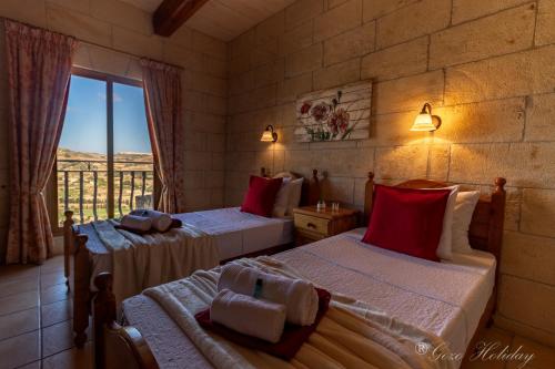 um quarto com 2 camas e almofadas vermelhas em Orchidea Xaghra em Il-Pergla