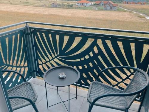 einen Tisch und Stühle auf einem Balkon mit Blick auf ein Feld in der Unterkunft Paradis Baile Felix in Baile Felix
