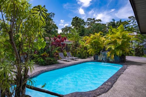 a swimming pool in a garden with chairs and trees at Hotel Sierra Arenal in Fortuna