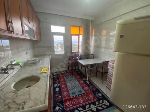a kitchen with a sink and a table and a refrigerator at Finike Apart in Finike