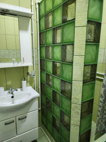 a bathroom with a sink and a green tiled wall at Apartman DUNJA in Pačir