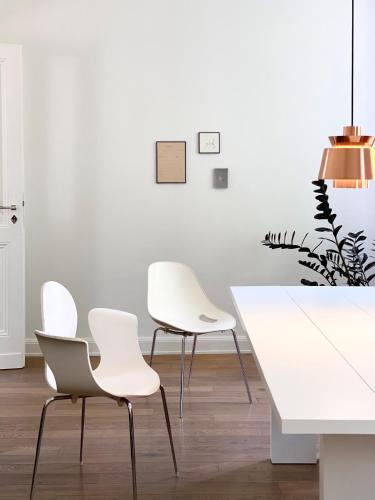 a dining room with white chairs and a white table at Zehuus mit Domblick und Dachterrasse in Cologne
