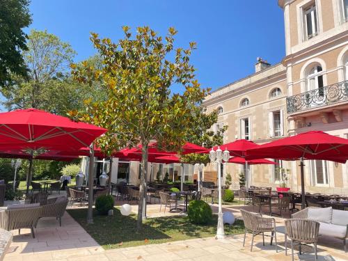 a group of tables with red umbrellas in front of a building at Chateau du Clos de la Ribaudiere - Teritoria in Chasseneuil-du-Poitou
