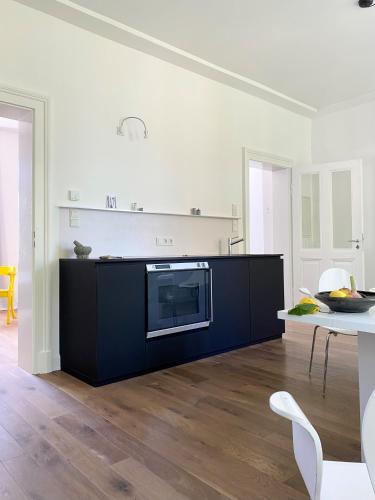 a white kitchen with a black cabinet and a table at Zehuus mit Domblick und Dachterrasse in Cologne