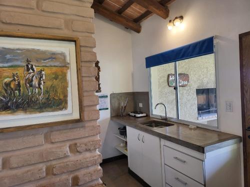 una cocina con encimera y una pintura en la pared en CASAS Viñedos de Cafayate Alquiler Temporario en Cafayate