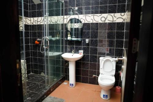 a black tiled bathroom with a toilet and a sink at DMK Apartments in Abuja