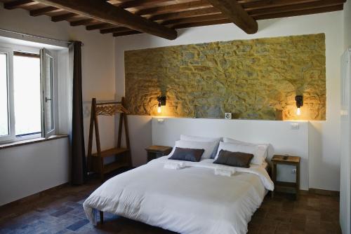 a bedroom with a large white bed with a stone wall at Le Dune rooms in Cinigiano